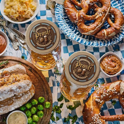 Round wooden Bavarian Prost Bierdeckel featuring 3D carved wood Prost lettering, a frothing beer glass, hop cone, accordion, and Bavarian flag border.